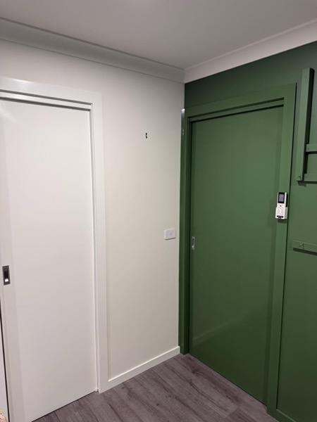 A deep green door set into a white hallway wall