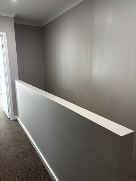 A landing with soft grey walls and a white capped balustrade