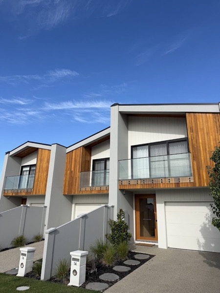 A row of townhouses with timber cladding and white garage doors