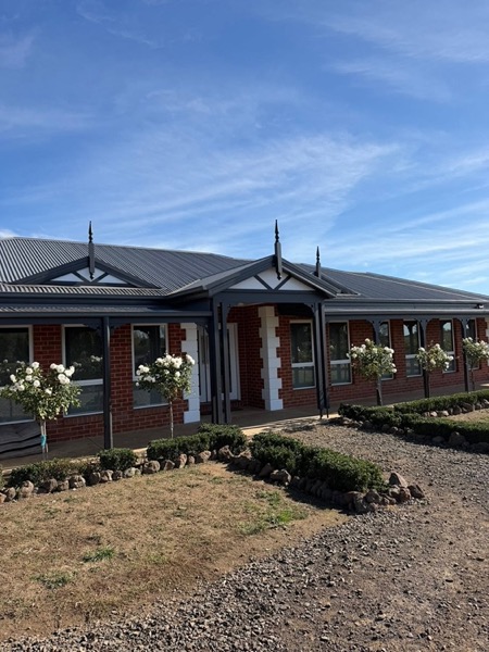 A brick homestead with gabled verandahs and a gravel garden bed