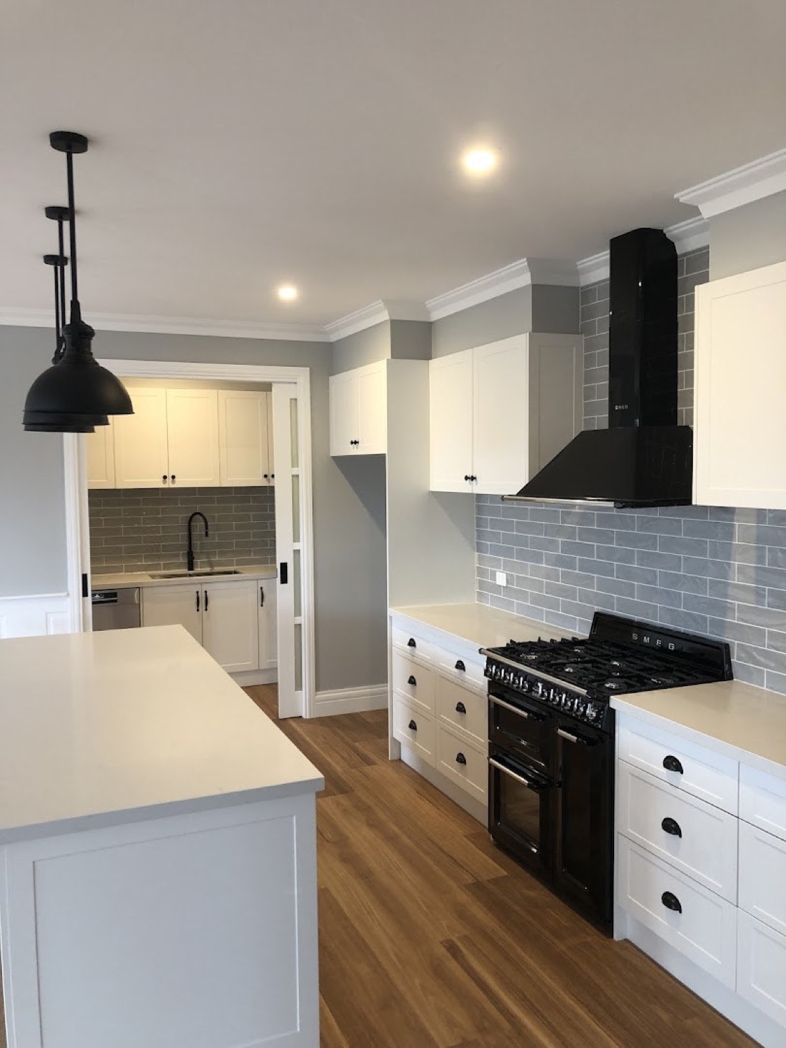 A kitchen with white cabinetry, a black range and a black rangehood
