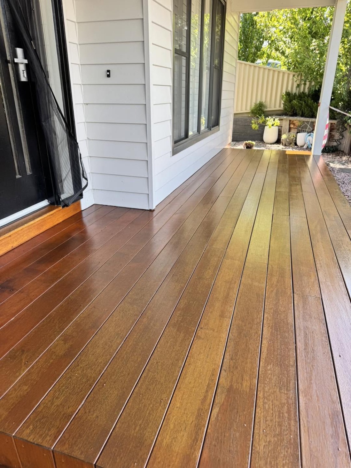 A timber deck running alongside a white weatherboard wall