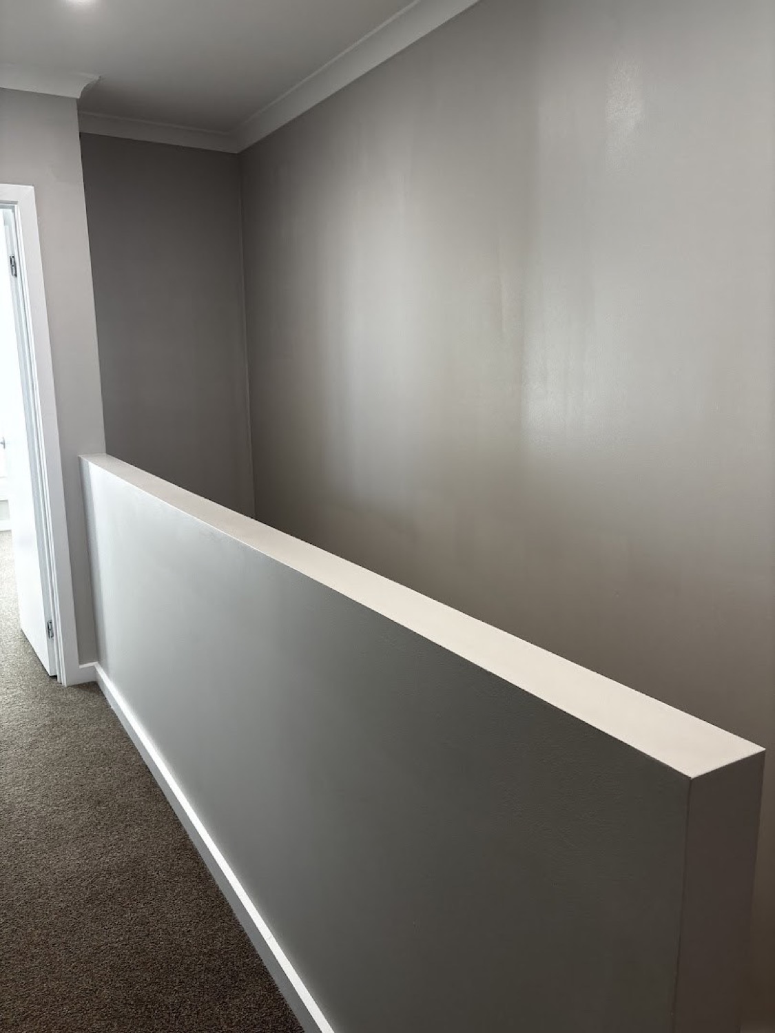 A landing with soft grey walls and a white capped balustrade