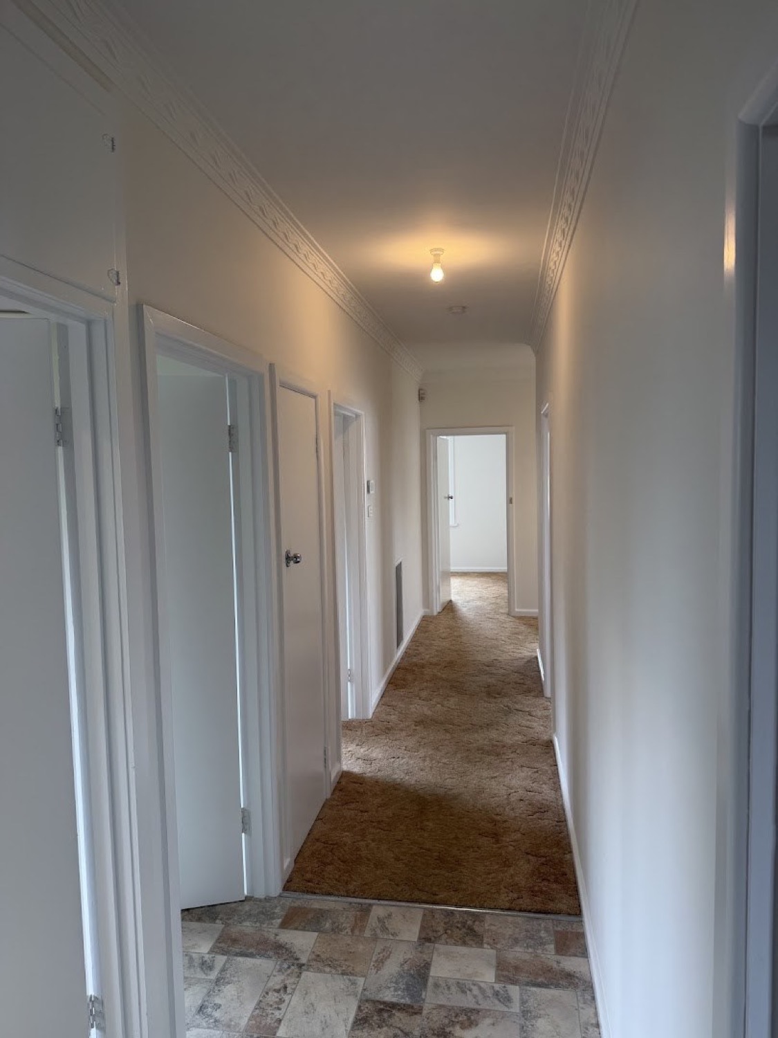 A white corridor with panel doors and white trims